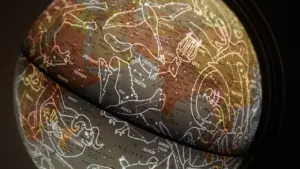 Tumšs globuss ar zvaigznājiem un astroloģiskajiem simboliem uz tumša fona.