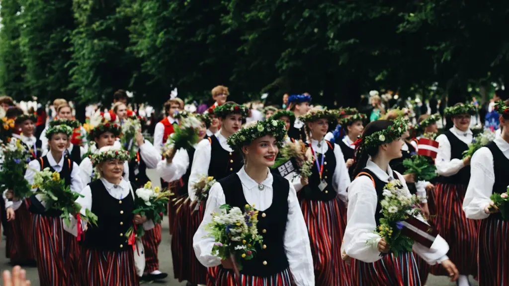 Latvijas tautu meitas tradicionālos tērpos piedalās svinīgā gājienā Rīgas ielās svētku laikā.